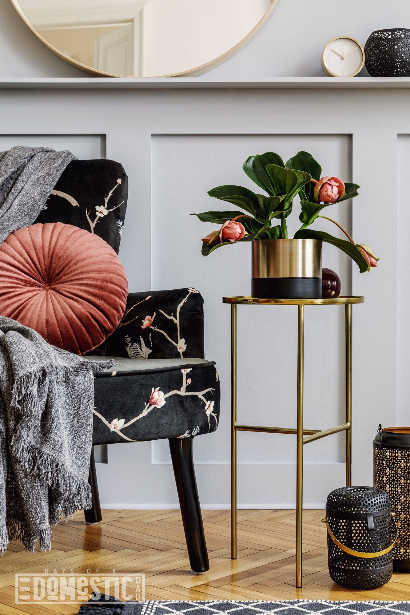 Modern concept of home staging with design armchair, round mirror, gold coffee table, pillow, plaid, lanterns, shlef, grey wall and elegant personal accessories at stylish living room.
