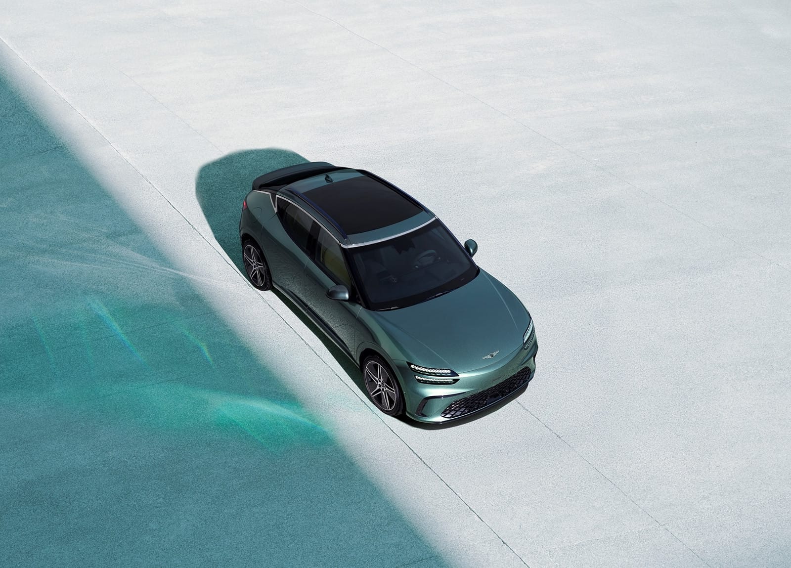 Overhead view of the Genesis GV60 Performance AWD electric SUV in green, highlighting its sleek roofline and modern design.