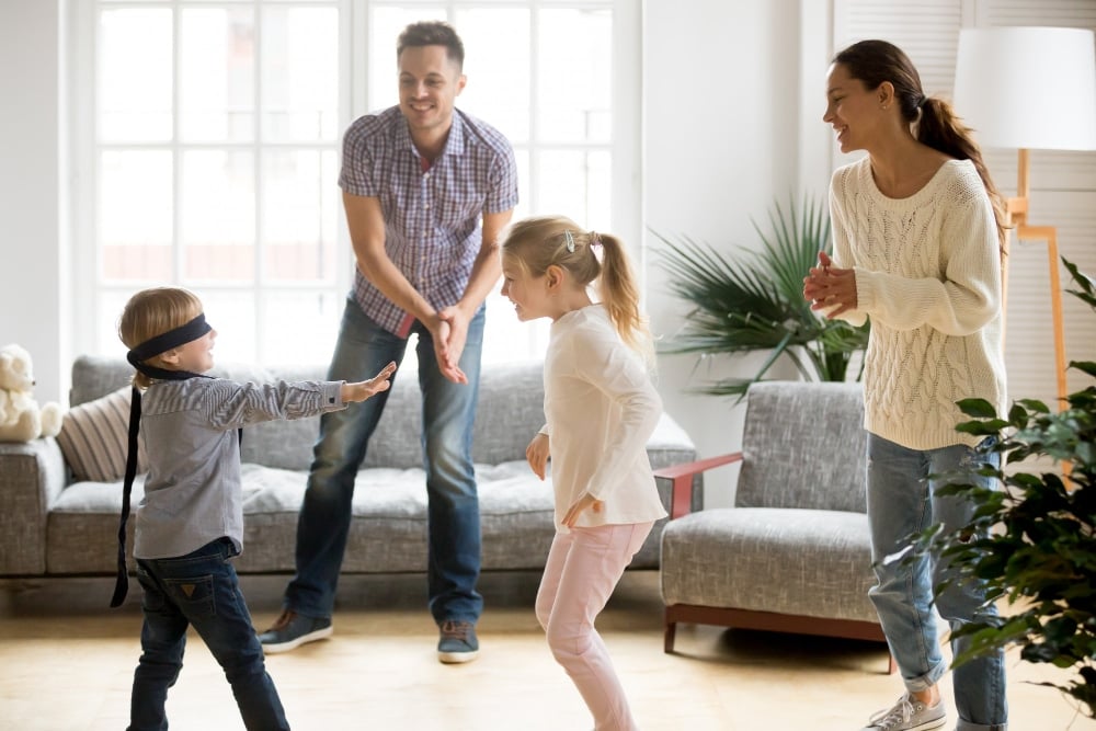 Free photo blindfolded cute boy playing hide and seek game with family