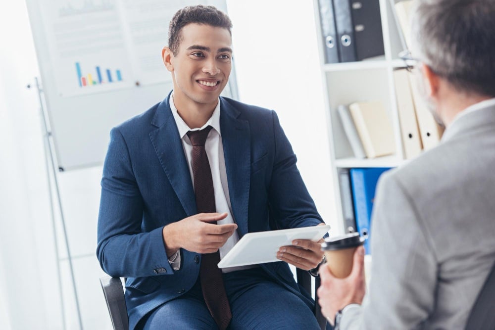 Photo cropped shot of smiling young businessman using digital tablet and looking at male colleague with