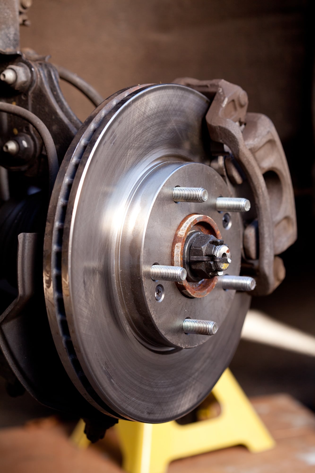 Close up shot of a newly replaced brake rotor and pads for a modern car