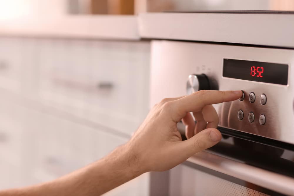 Man adjusting electric oven in kitchen, closeup