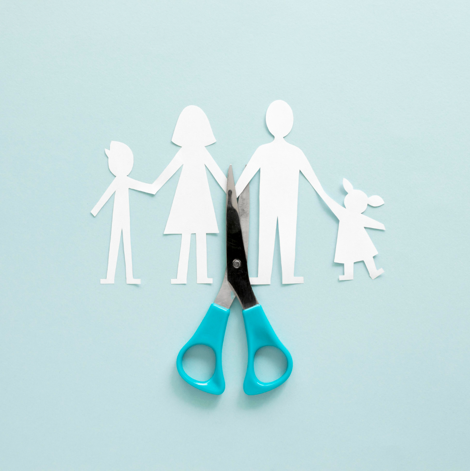 Paper cutout figures of a family with a pair of scissors cutting through them, symbolizing family separation and child support issues.