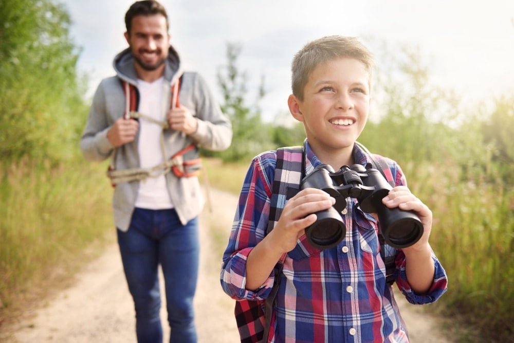 father and son walking on a dirt trail looking for wild life