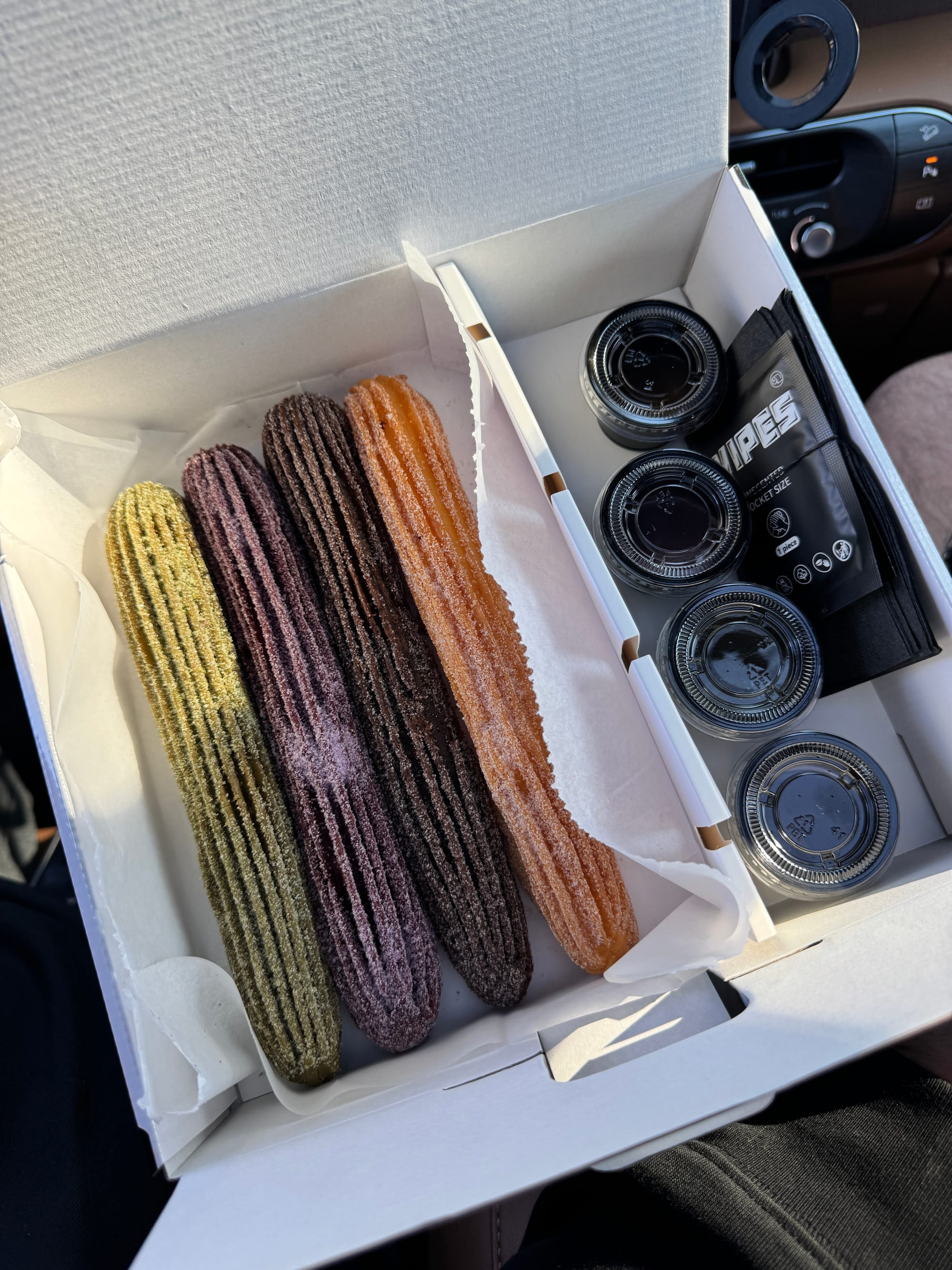Family box from IYKYK Mochi Churros with four mochi churros and assorted dipping sauces, a popular gluten-free dessert option in Dallas.