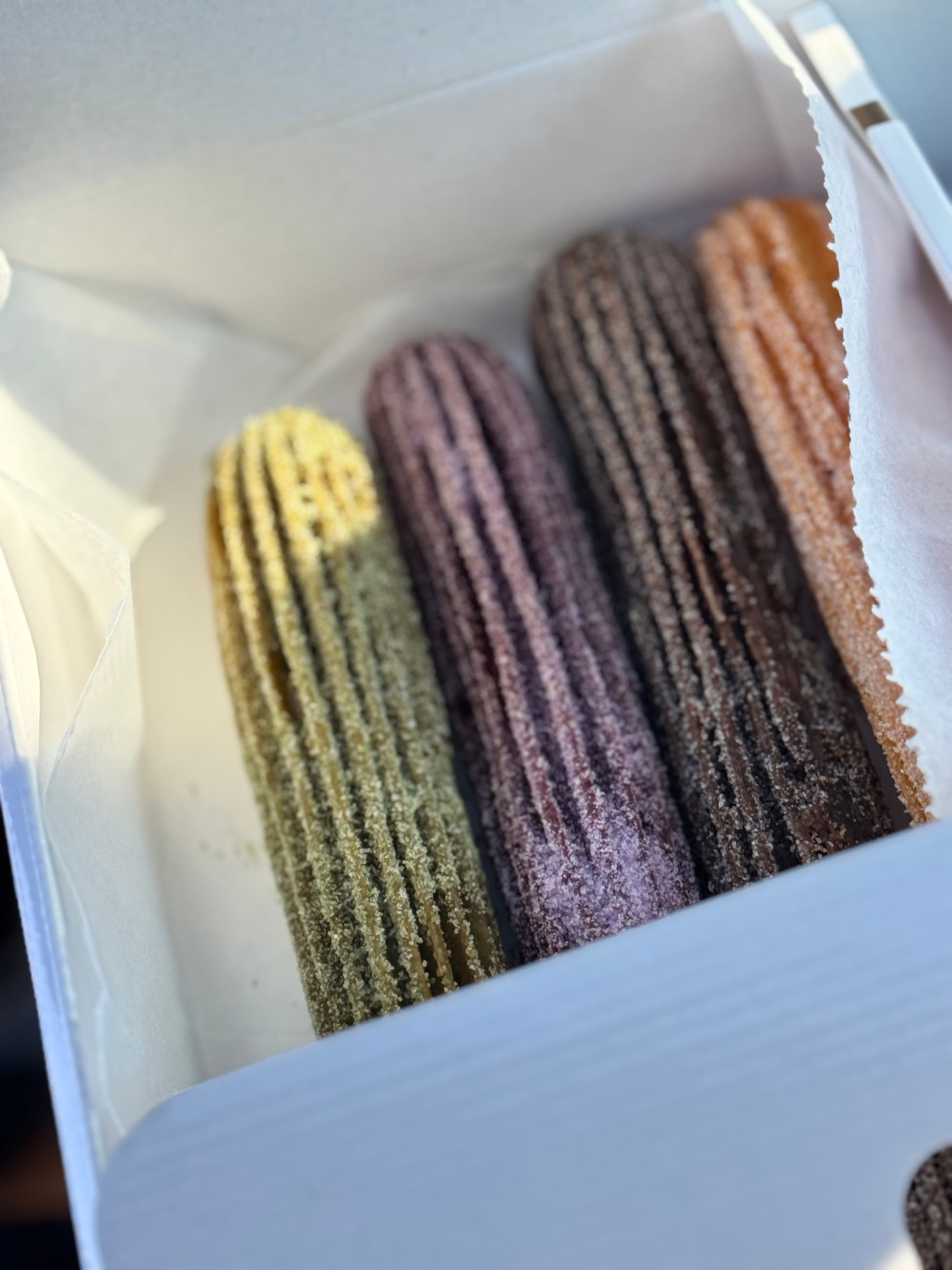Box of IYKYK Mochi Churros featuring original, ube, matcha, and chocolate flavors at the Dallas Regal Row location.