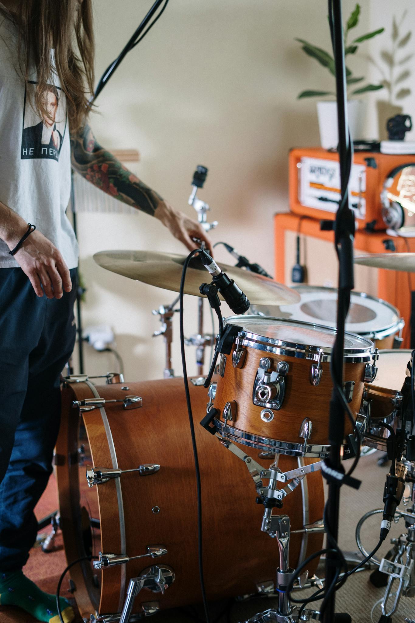 Man setting up a drum set in a cozy home music studio, capturing an artistic vibe.