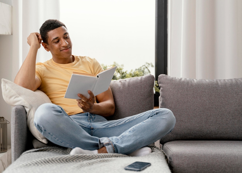 Male reading a book on the couch