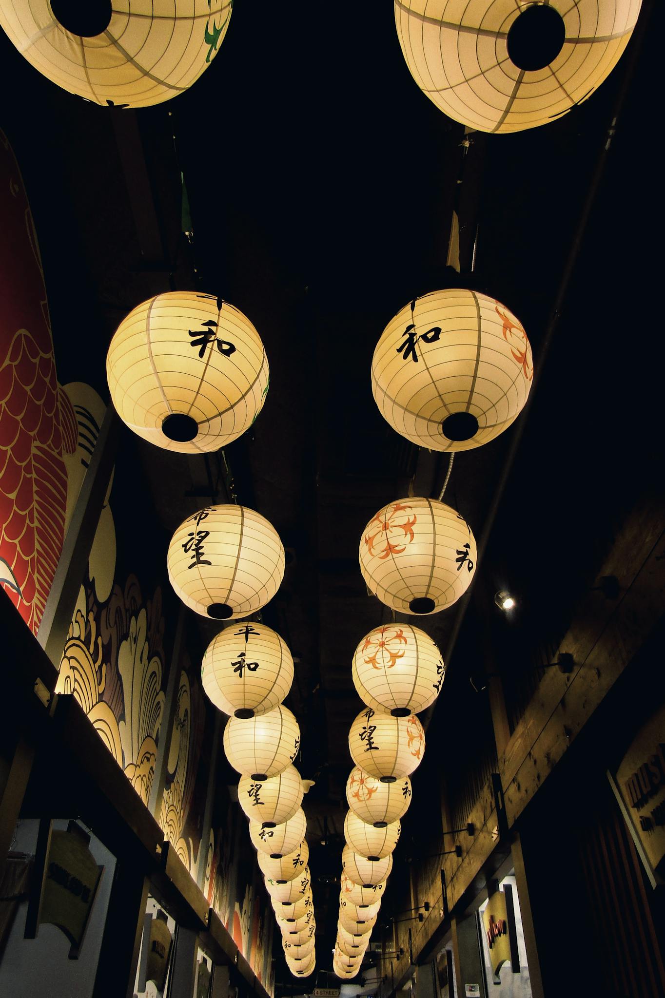 Rows of traditional Japanese paper lanterns glowing warmly in the night.