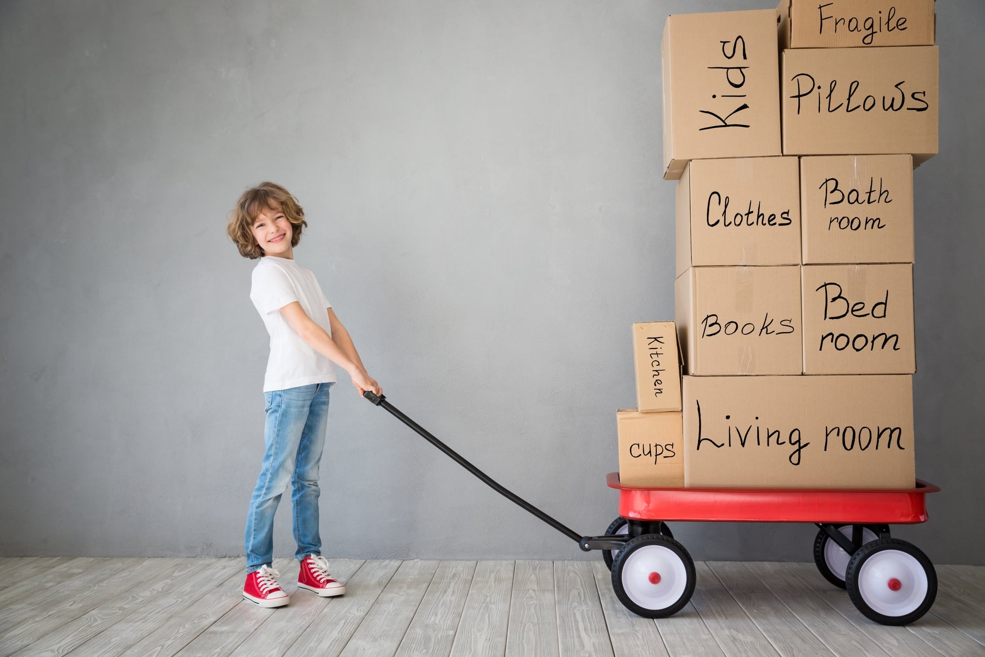Happy child playing into new home. Kid having fun indoor. Moving house day and express delivery concept