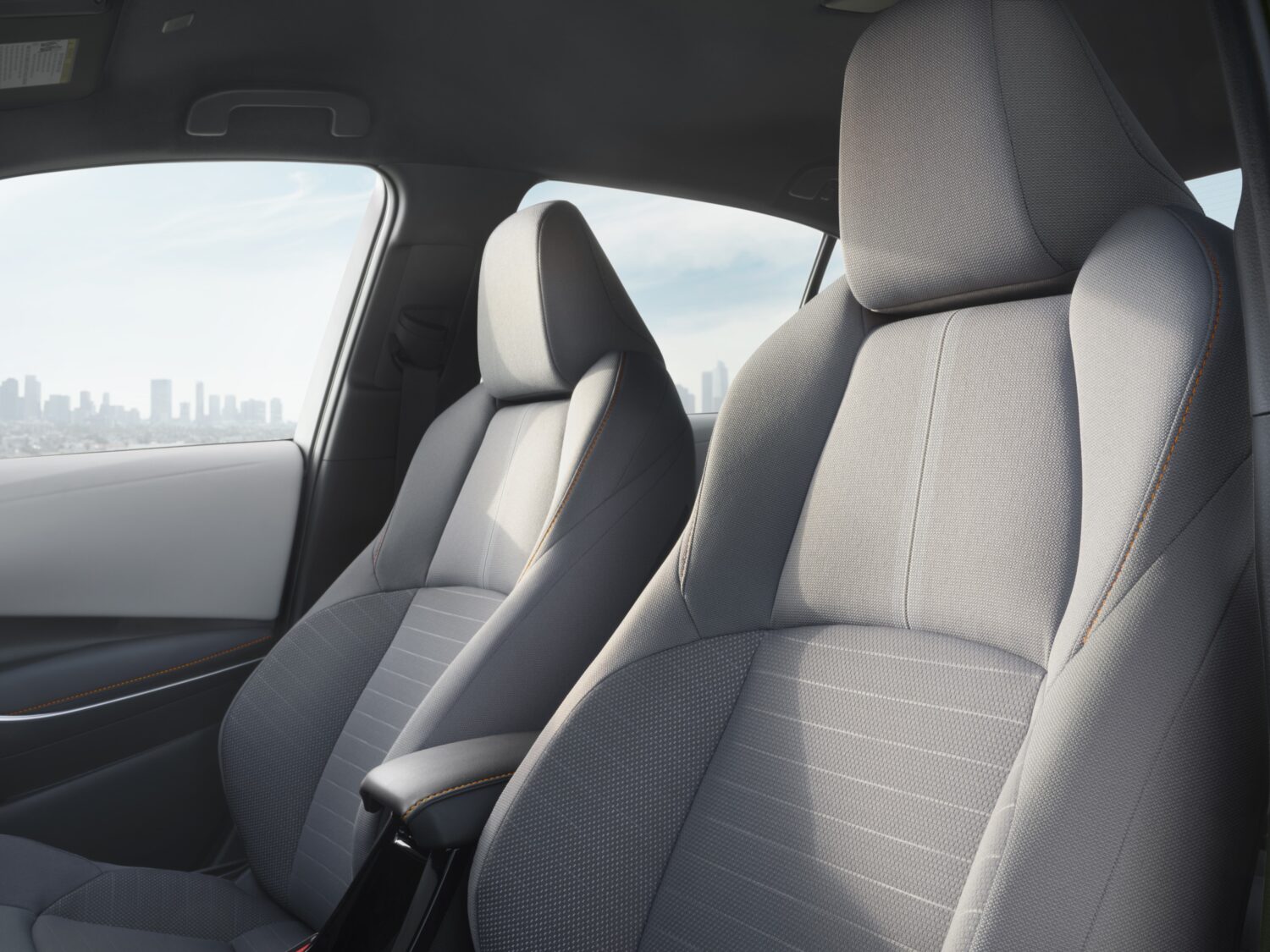 Front sport seats of the 2025 Toyota Corolla FX with Moonstone fabric and orange stitching