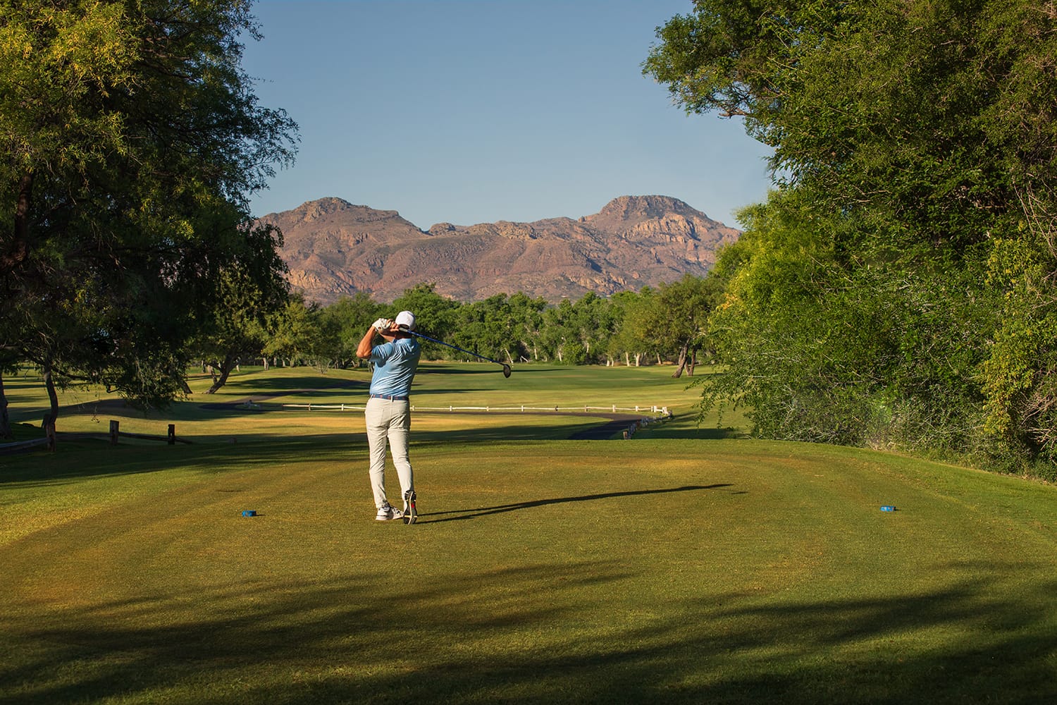Golfer teeing off at Tubac Golf Resort with mountain views and lush fairways in southern Arizona