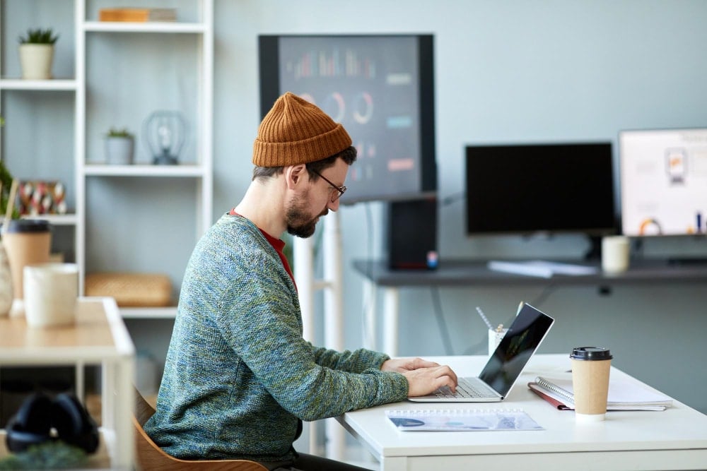 Young male employee or designer sitting by desk in front of laptop, Work and Family Life