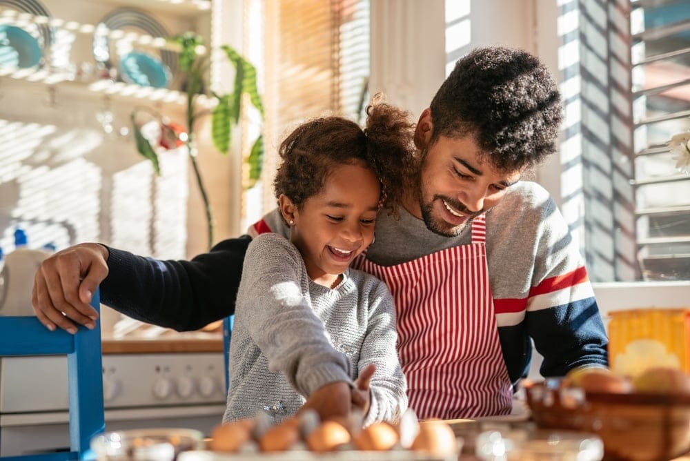 Dad teaching his daughter cooking measurements while preparing food together in the kitchen