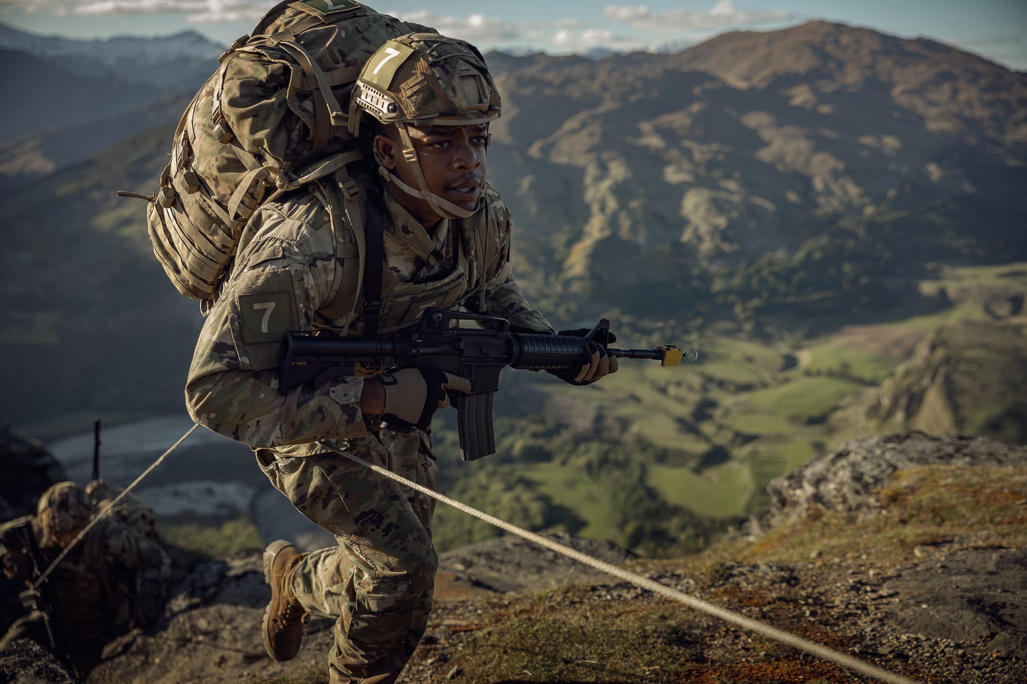 Army Ranger recruit climbing mountain during training mission in the Netflix movie War Machine