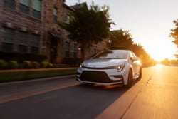 2026 Toyota Corolla Cross XLE AWD driving on city road during sunset exterior view