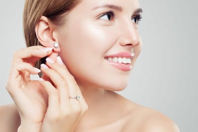 Beautiful bride in puts on diamond earring. Beauty model girl in wedding jewelry, perfect face closeup