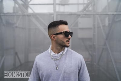 Stylish young attractive man wearing a sweater over a shirt with necklaces and sunglasses