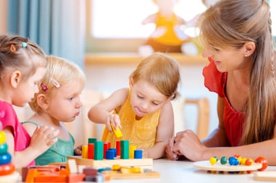 Group of children and teacher playing practical games in kindergarten