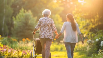 Senior woman and caregiver enjoying a peaceful walk in a sunny garden
