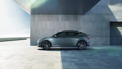 Side profile of the Genesis GV60 Performance AWD parked in a modern architectural setting, emphasizing its sporty stance.