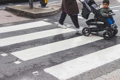 A child in a stroller crossing a zebra crossing in the city. Urban street scene focusing on pedestrian safety.
