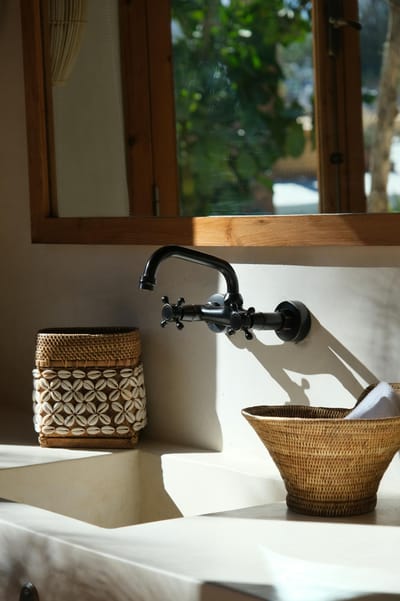 A sunlit bathroom with Mediterranean decor featuring woven baskets and elegant fixtures.