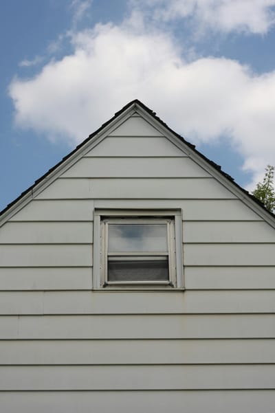 A traditional house gable with a small window against a clear blue sky in Ottawa, Canada.