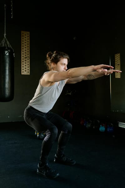 A young man performing squats in an indoor gym setting focusing on fitness and strength training.