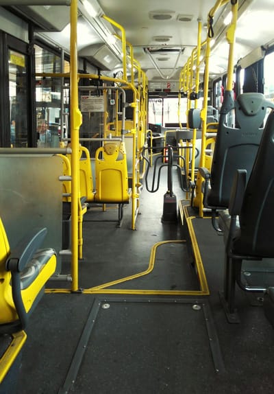 An empty bus with yellow seats and handrails in São Paulo, highlighting urban transportation.