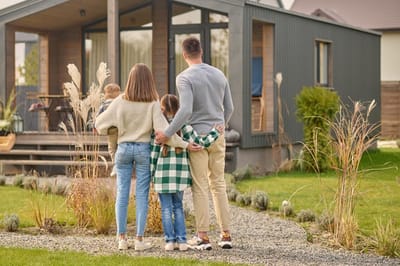 view of family hugging and admiring their home