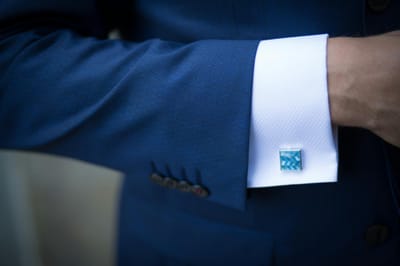 Close-up of a blue suit sleeve with decorative cufflinks, showcasing elegance.