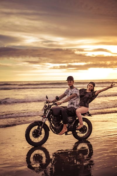 Young male and female riding a motorcycle on the beach sunset