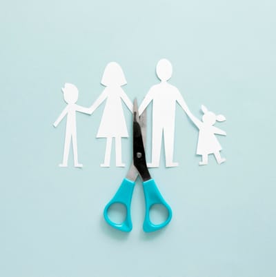 Paper cutout figures of a family with a pair of scissors cutting through them, symbolizing family separation and child suppor