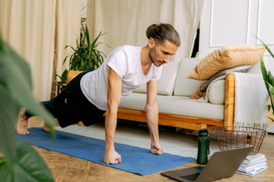 Man doing push-ups indoors on a yoga mat, engaging in a healthy lifestyle using online fitness resources.