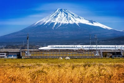 Shinkansen bullet train passing in front of snow-capped Mount Fuji in Japan