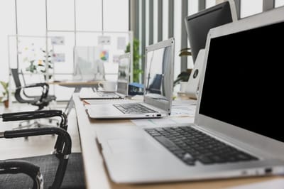 Photo selective focus on laptops sitting on conference table in meeting room office with multiple glass windows in background
