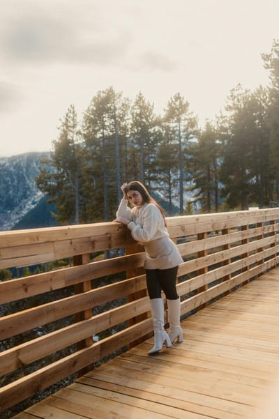 Stylish woman posing on a scenic footbridge with mountain views in Andorra la Vella.