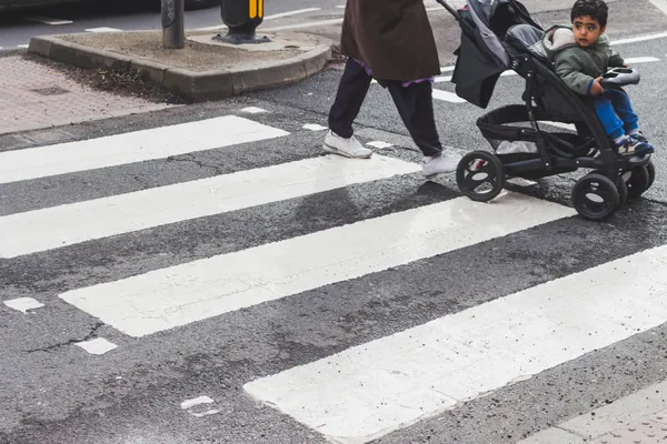 A child in a stroller crossing a zebra crossing in the city. Urban street scene focusing on pedestrian safety.