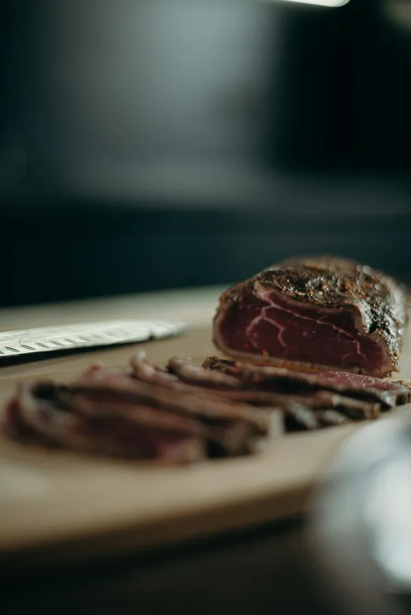 A close-up view of sliced red meat on a wooden cutting board, ideal for culinary and food-related needs.