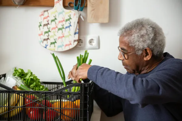An Elderly Man in Sweater Holding Vegetables