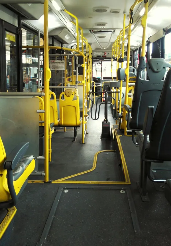 An empty bus with yellow seats and handrails in São Paulo, highlighting urban transportation.