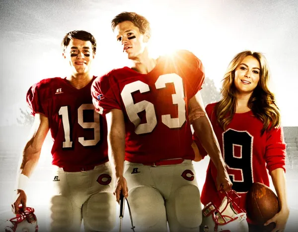 Promotional image from 23 Blast featuring three main characters standing together on a football field. Two young men wear red