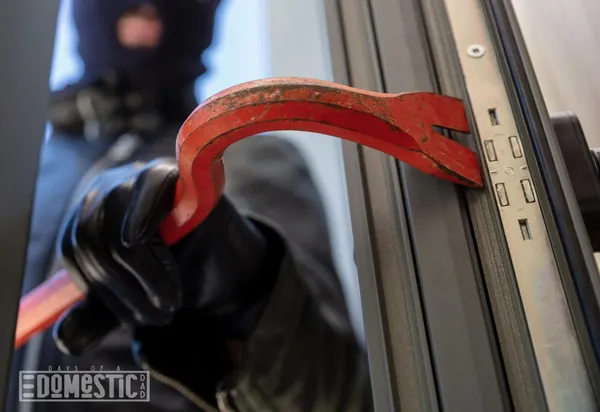 Photo bandit in balaclava holding a crowbar to break a glass window
