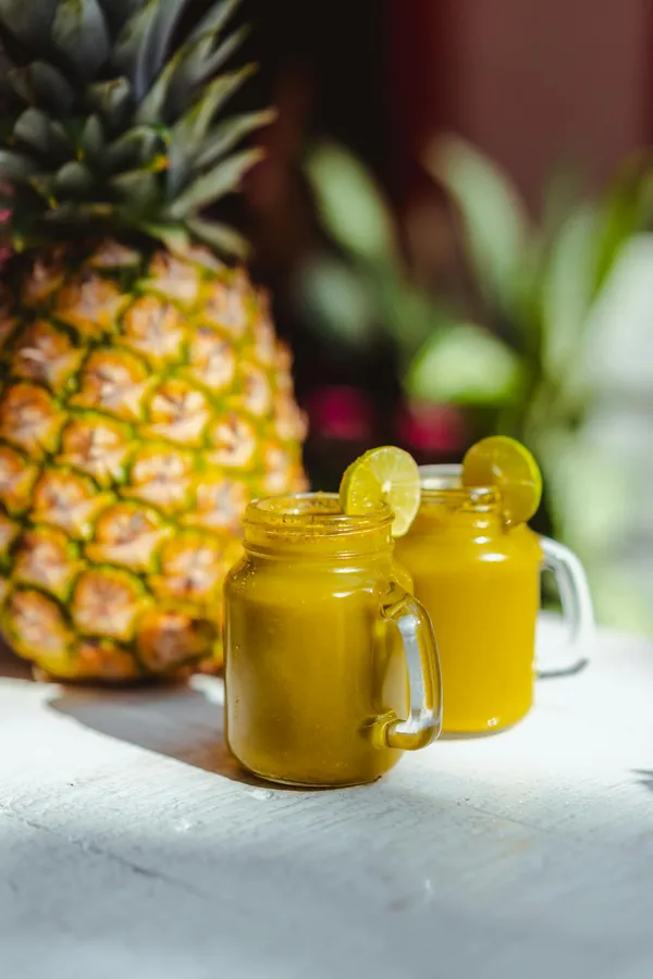 Delicious and nutritious pineapple juice served in mason jar glasses with fresh pineapple.