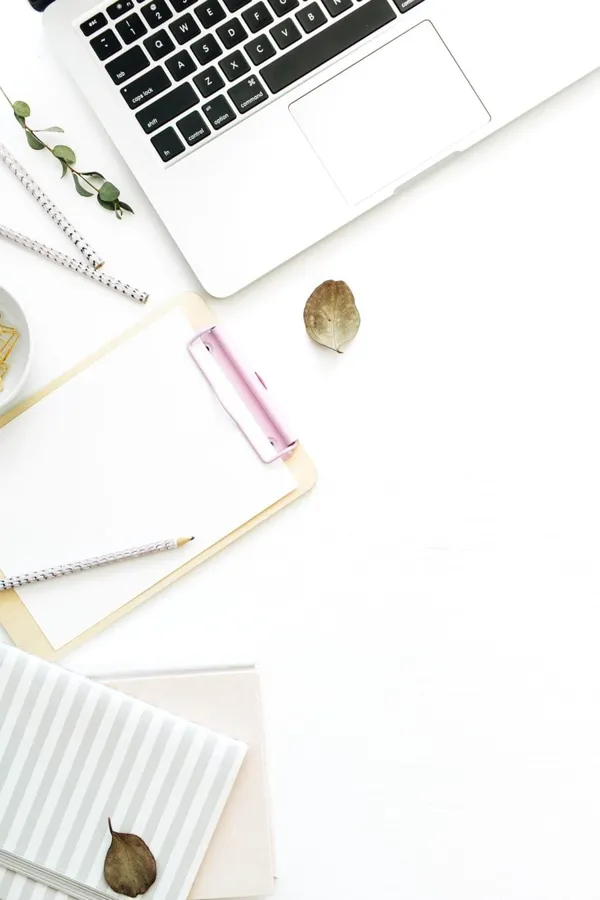 clean white desk with laptop daily planner and note pad
