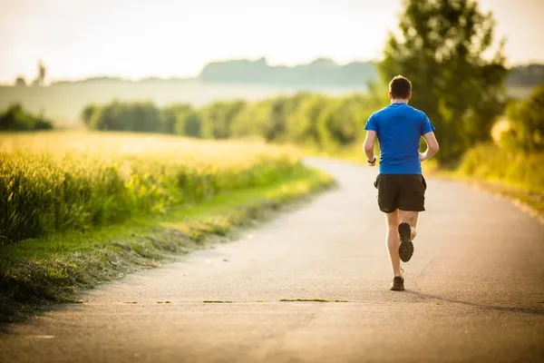 Male athlete/runner running on road - jog workout well-being concept