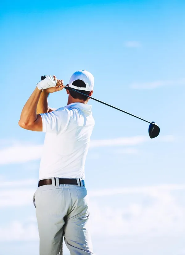 Man Swinging Golf Club with Blue Sky Background