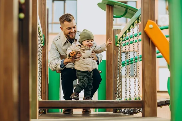 Father with baby son on play ground having fun