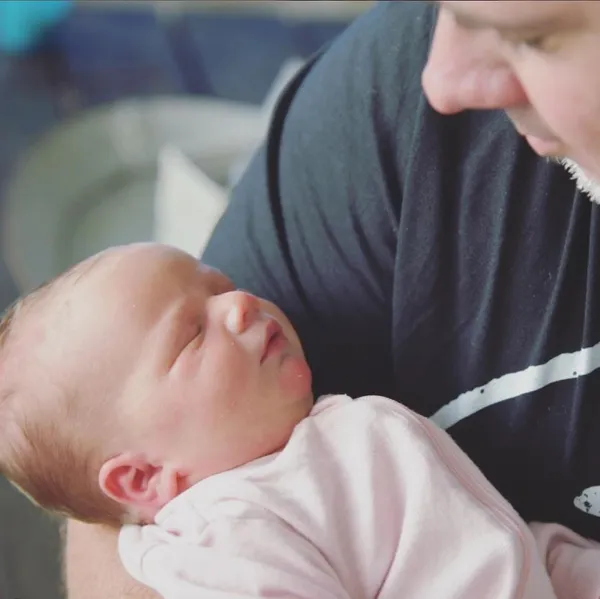 First-time dad lovingly holding his newborn baby in his arms.